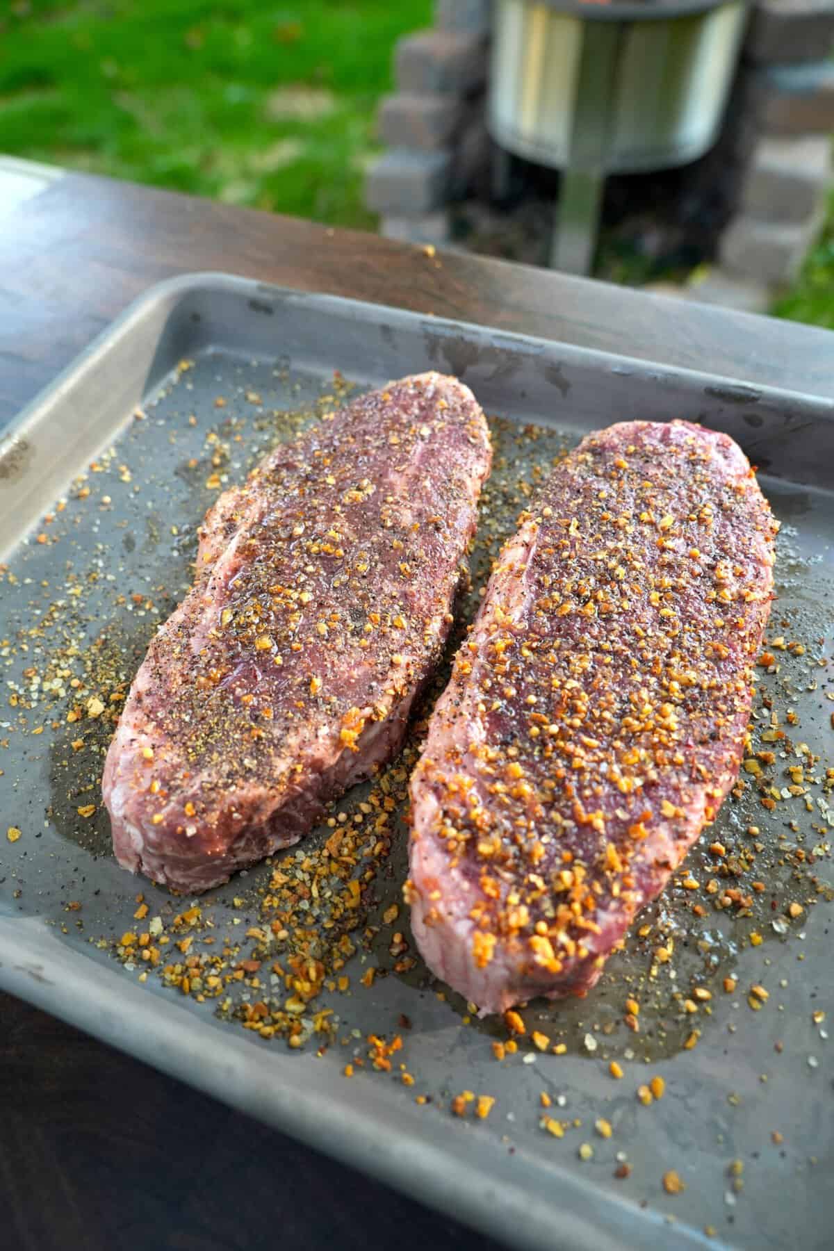 Two raw steaks on a baking sheet, seasoned with Salt Pepper Garlic for Alfredo Steak and Fries